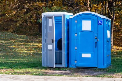 One ADA-accessible and one single use portable toilet in a park.